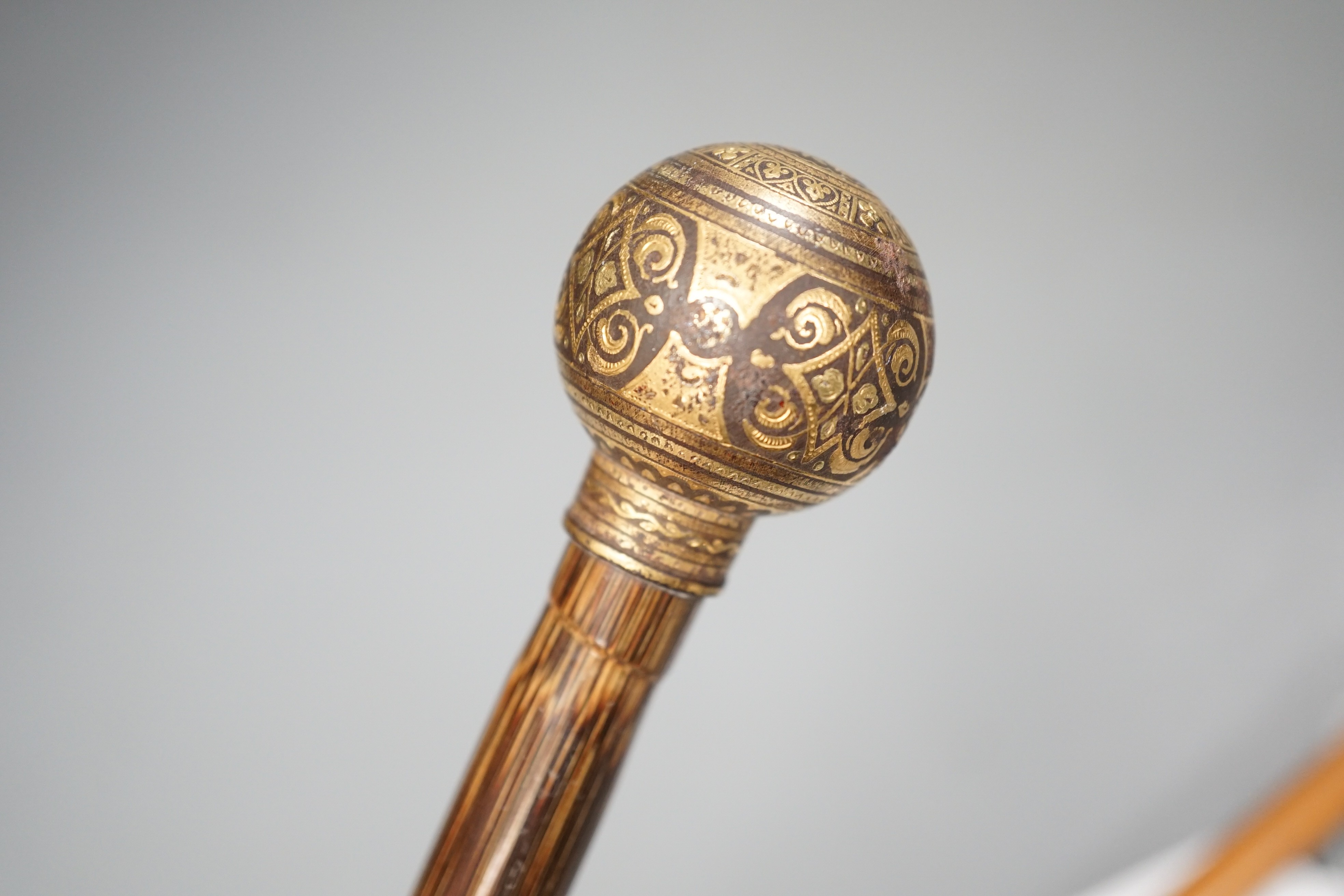 An early 20th century ivory ‘sphinx’ parasol handle, 84cm, together with another gold and iron damascened parasol handle, 62cm